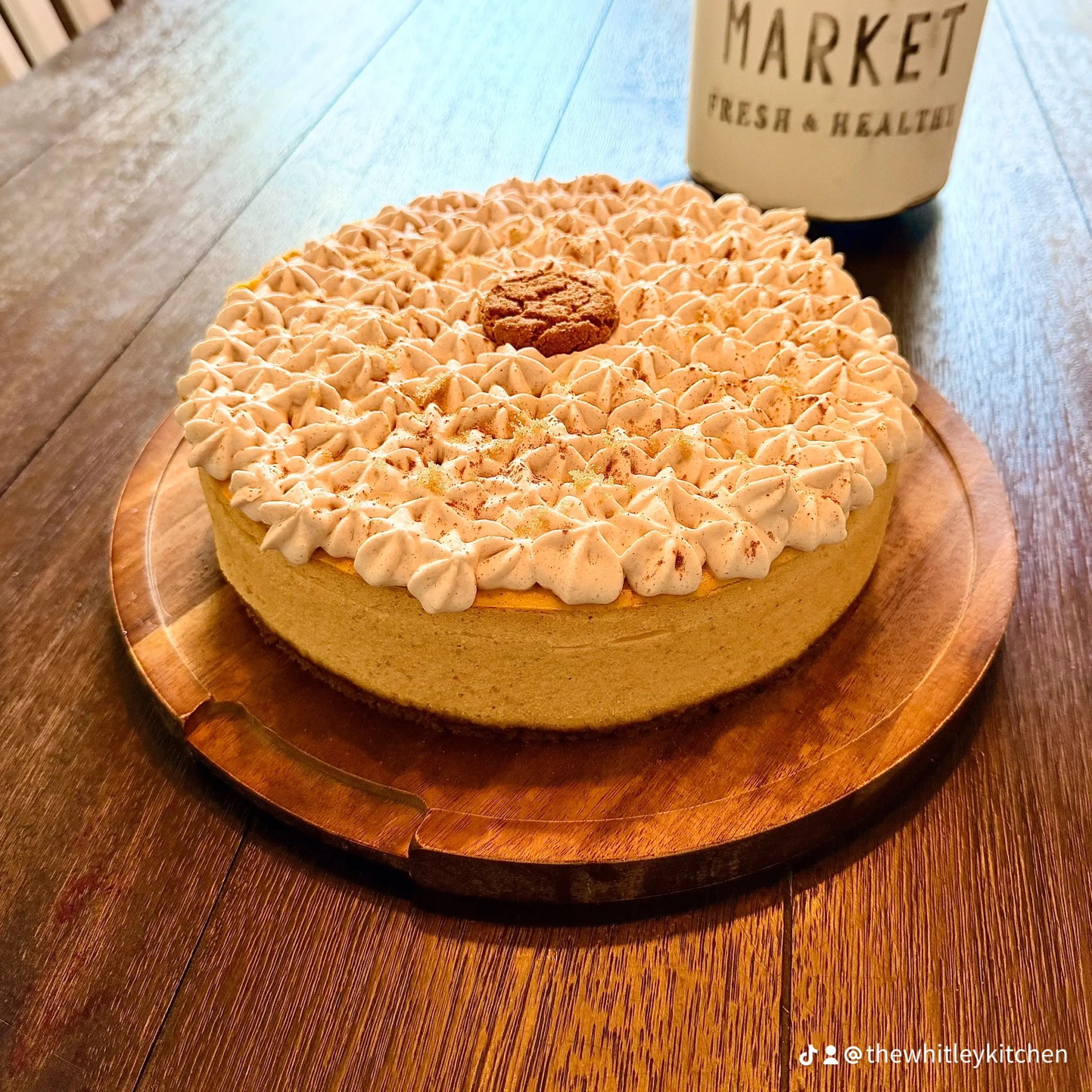 Close-up of Autumn Spice Cheesecake with brown sugar cinnamon whipped cream rosettes and a gingersnap on top