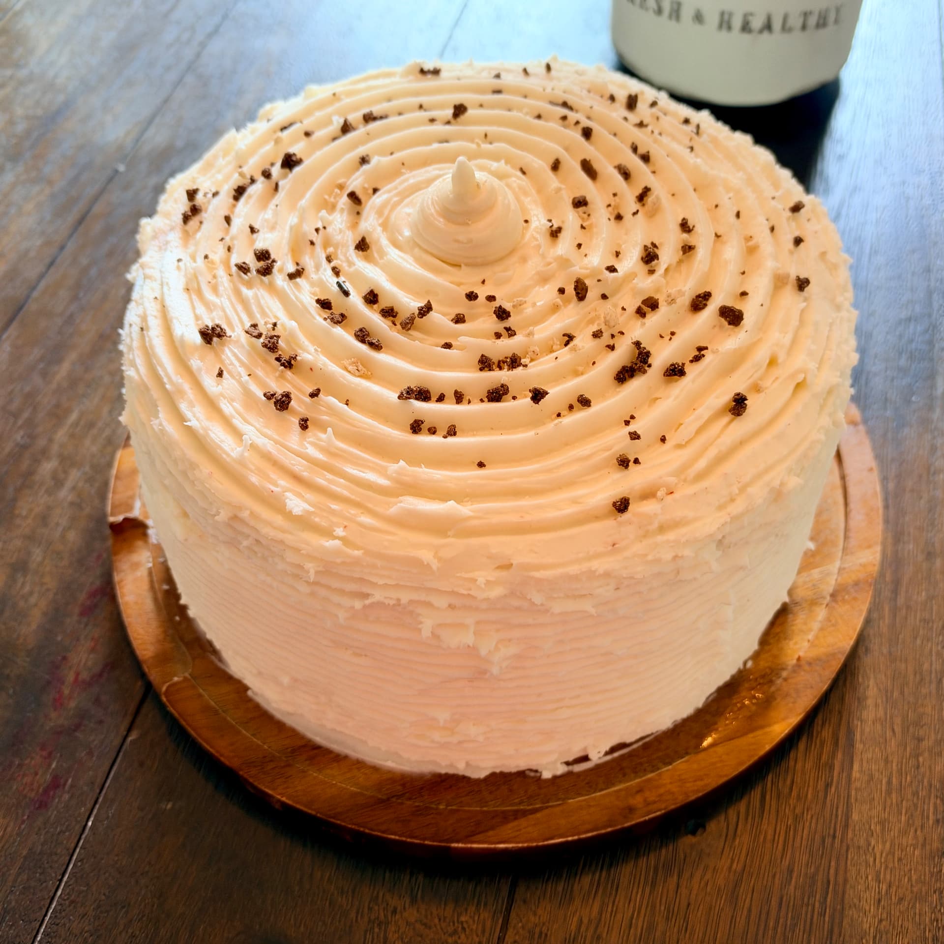 Close-up of the finished Southern Red Velvet Showstopper Cheesecake with swirled cream cheese frosting and cookie crumbs