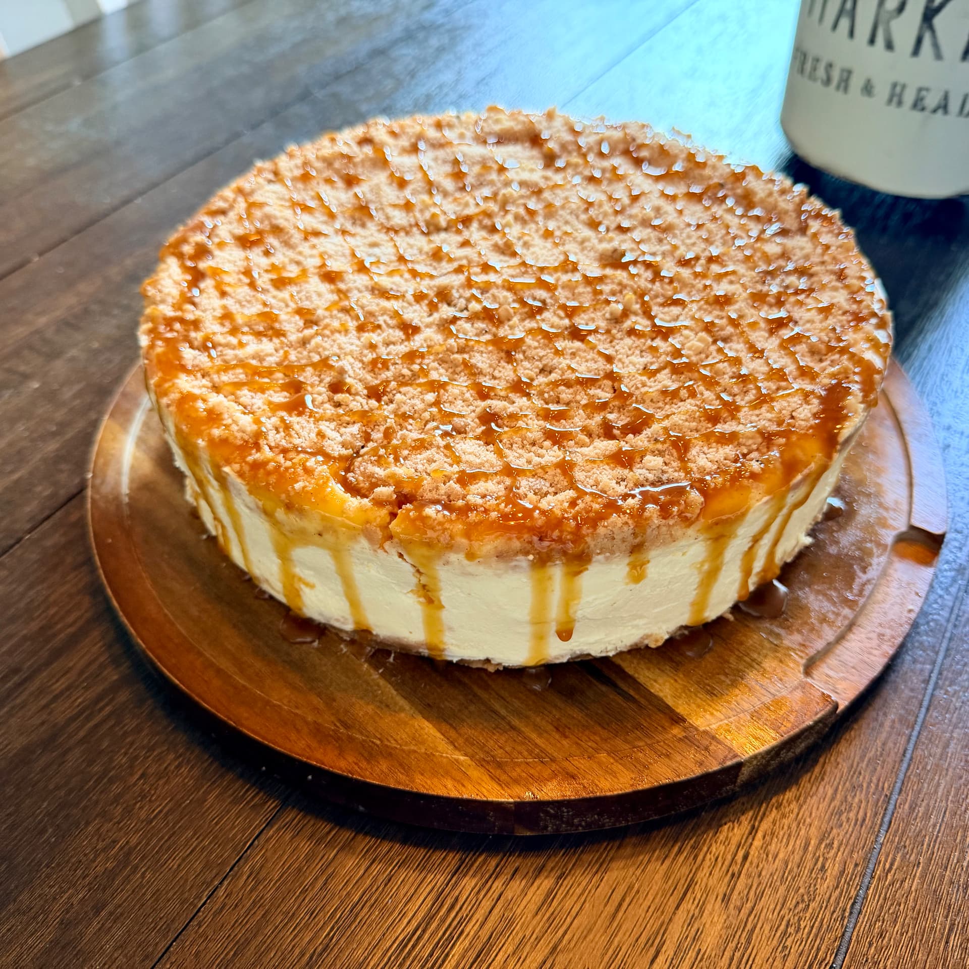 Close-up of Apple Pie Cheesecake with cinnamon crumble topping and caramel drizzle on a wooden board