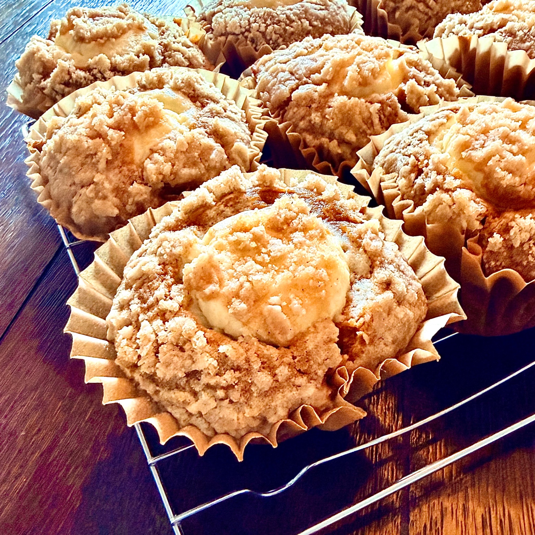 Close-up of a Pumpkin Cream Cheese Muffin with streusel topping and a cream cheese center on a cooling rack