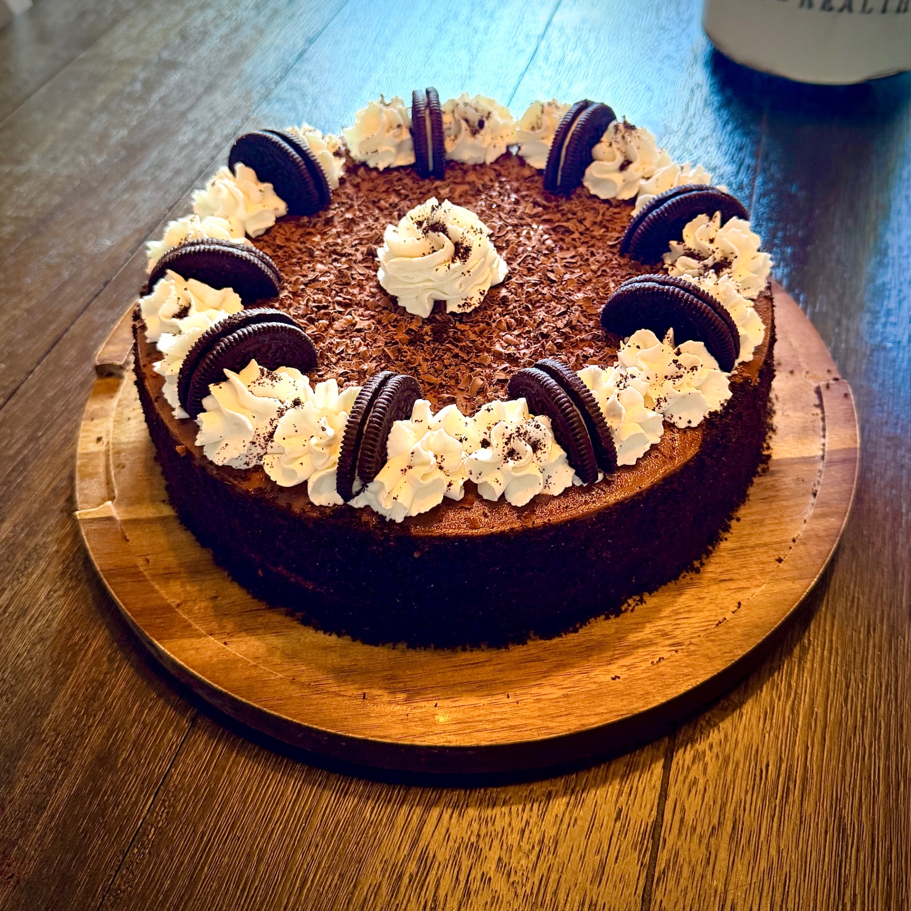 Close-up of Chocolate Fudge Cheesecake topped with chocolate shavings, whipped cream rosettes, and Oreo halves